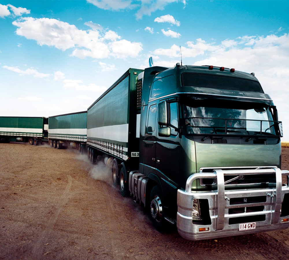 Volvo FH puxando conjunto carregado em estrada de terra batida.